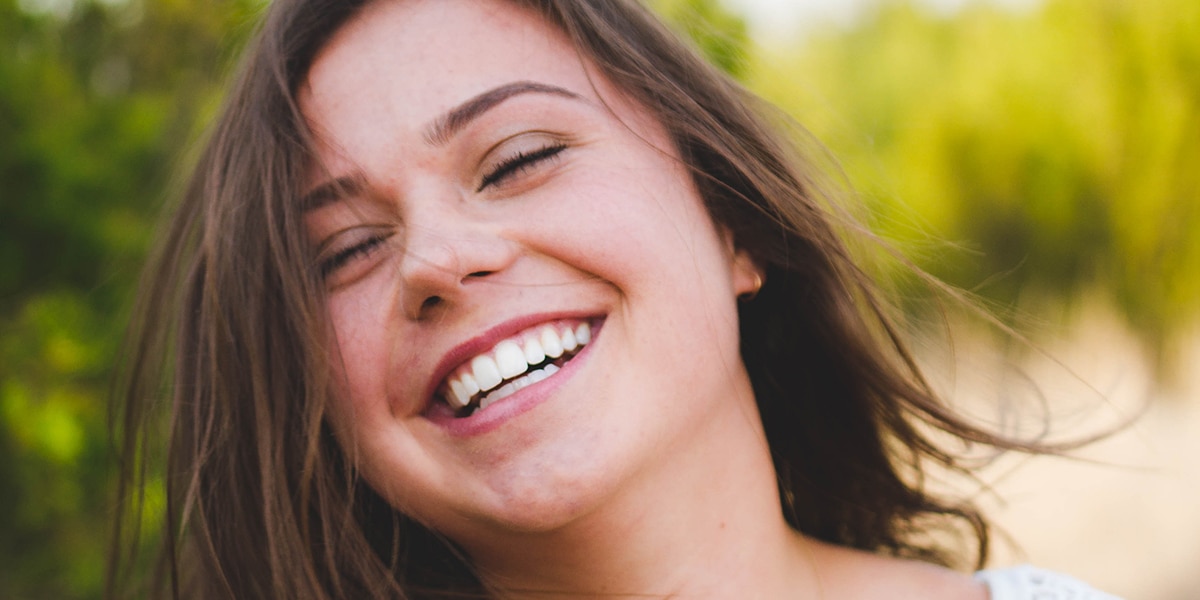 Lächelnde junge Frau vor Naturkulisse