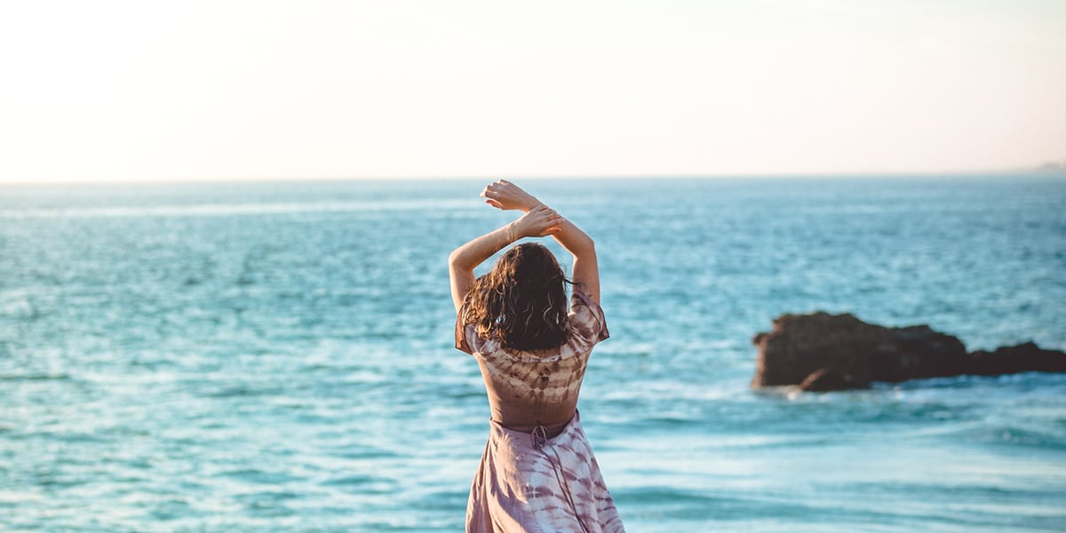 Frau mit hochgehobenen Armen am Meer