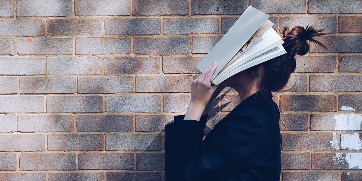 Frau hält sich ein aufgeschlagenes Buch vor ihr Gesicht