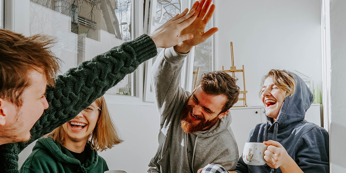 Lachende Gruppe junger Menschen, zwei geben sich ein High Five